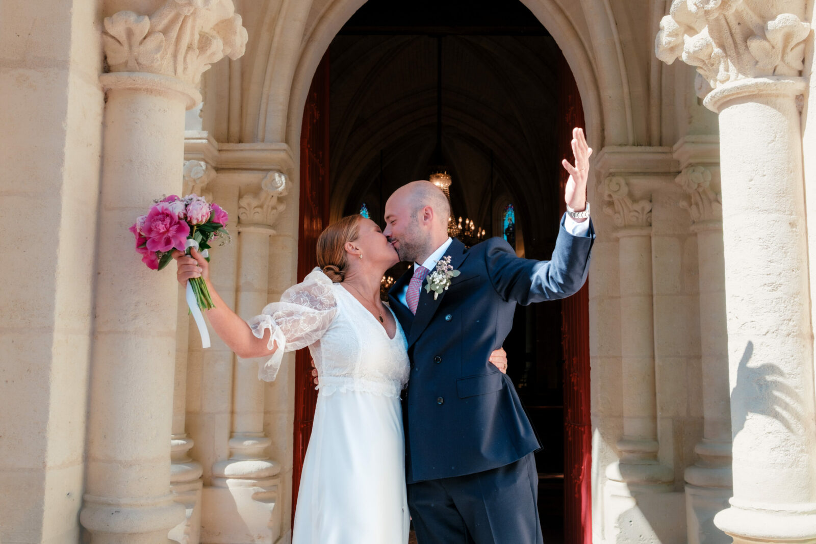 Couple de mariées sortant de l'église. La mariée porte une robe de mariée sur mesure en soie 